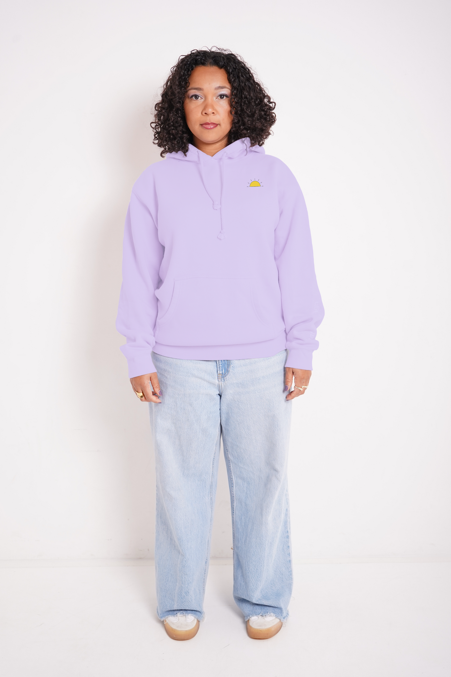 Person wearing a light purple hoodie with a small logo and light blue jeans on a white background