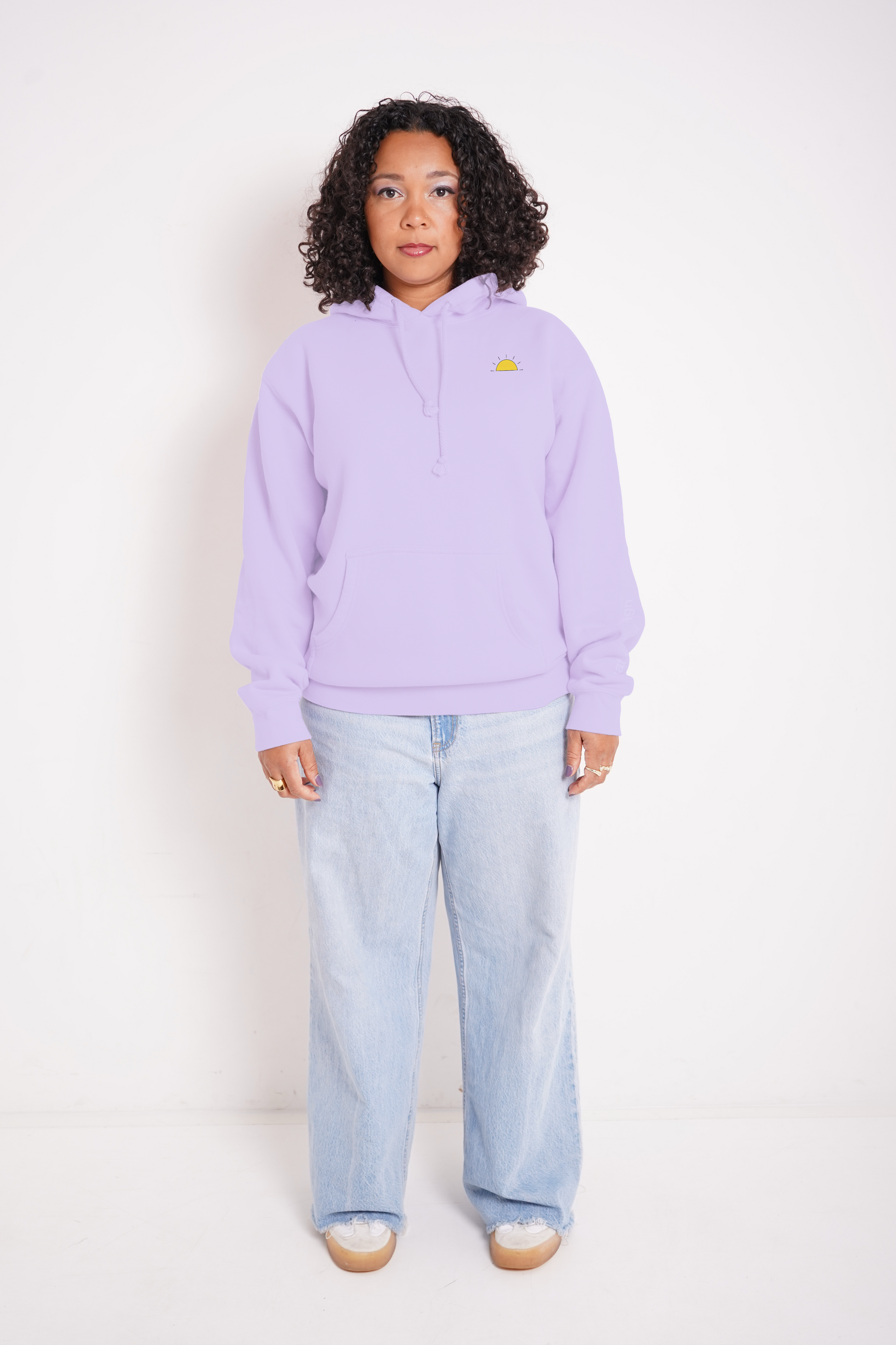 Person wearing a light purple hoodie with a small logo and light blue jeans on a white background